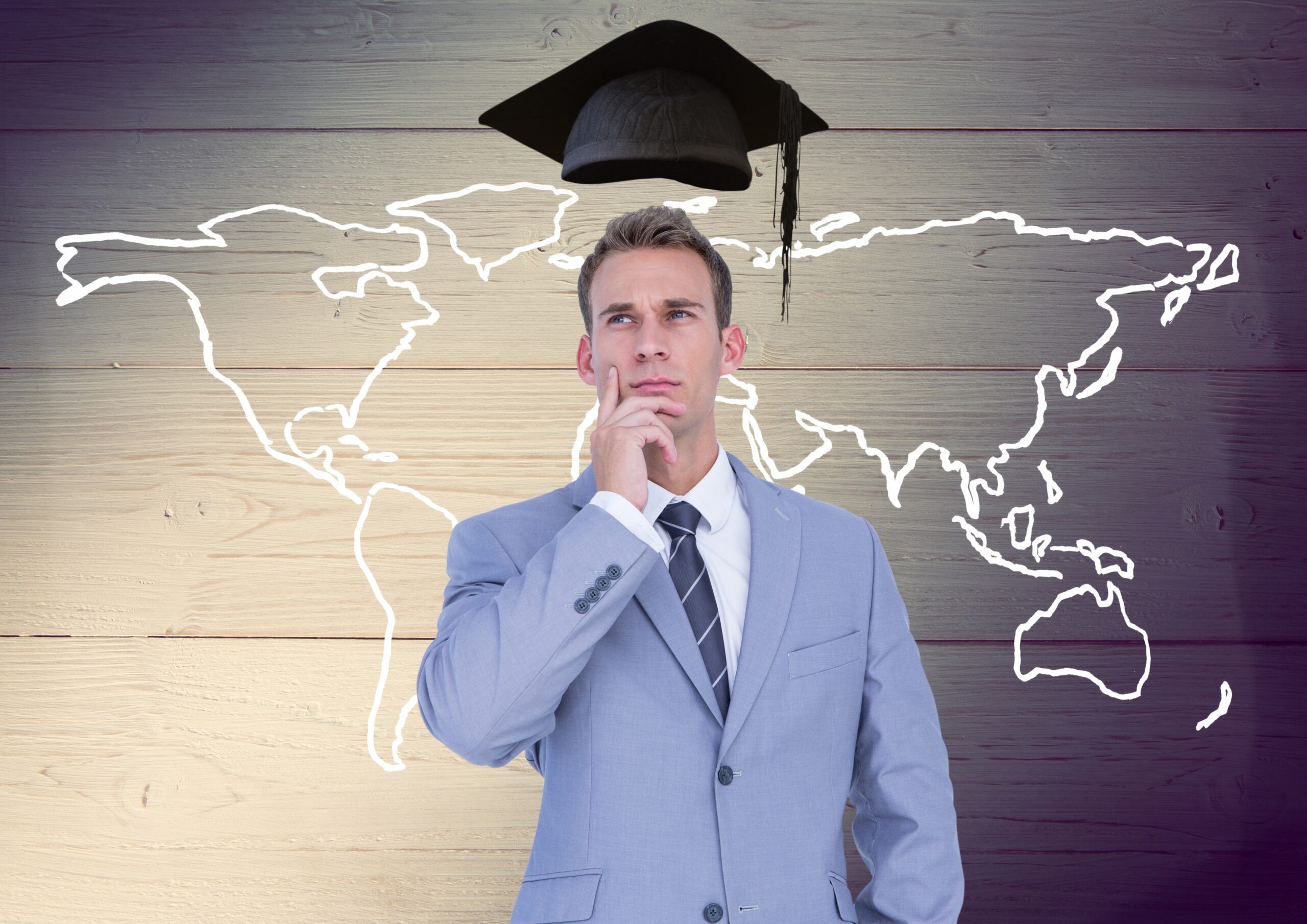 Businessman with mortarboard above head and world map against wooden background